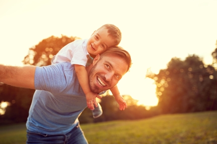 Father and son laughing with the son on the father's back 